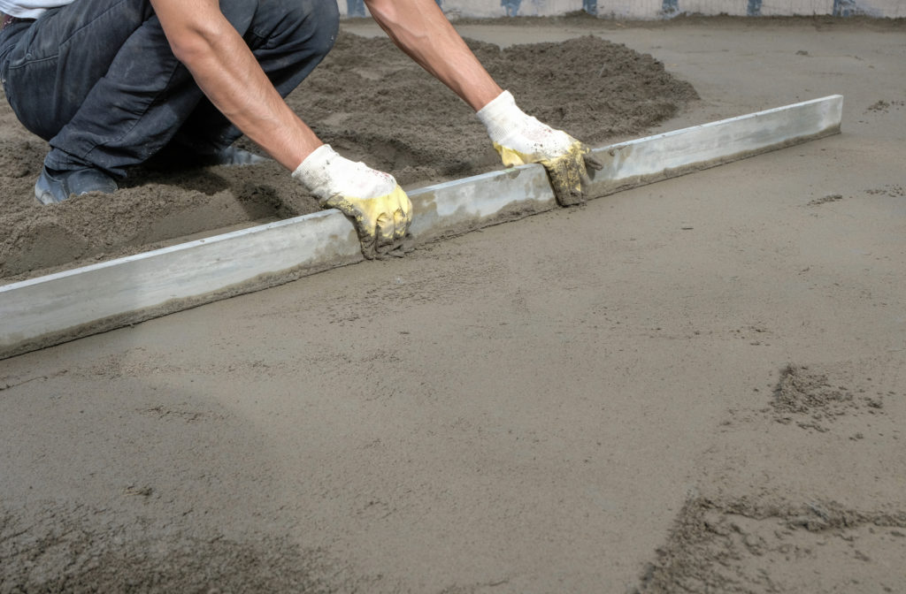 Construction worker using a tool to smooth out fresh concrete