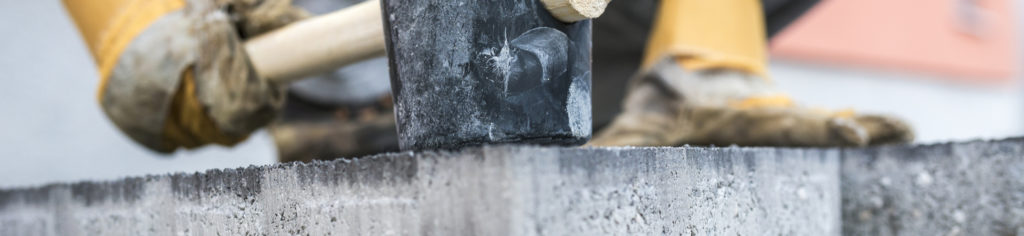 a construction worker hammering the corner of a foundation slab with a mallet
